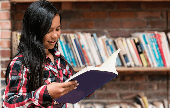 Teen girl reading a book in the library.