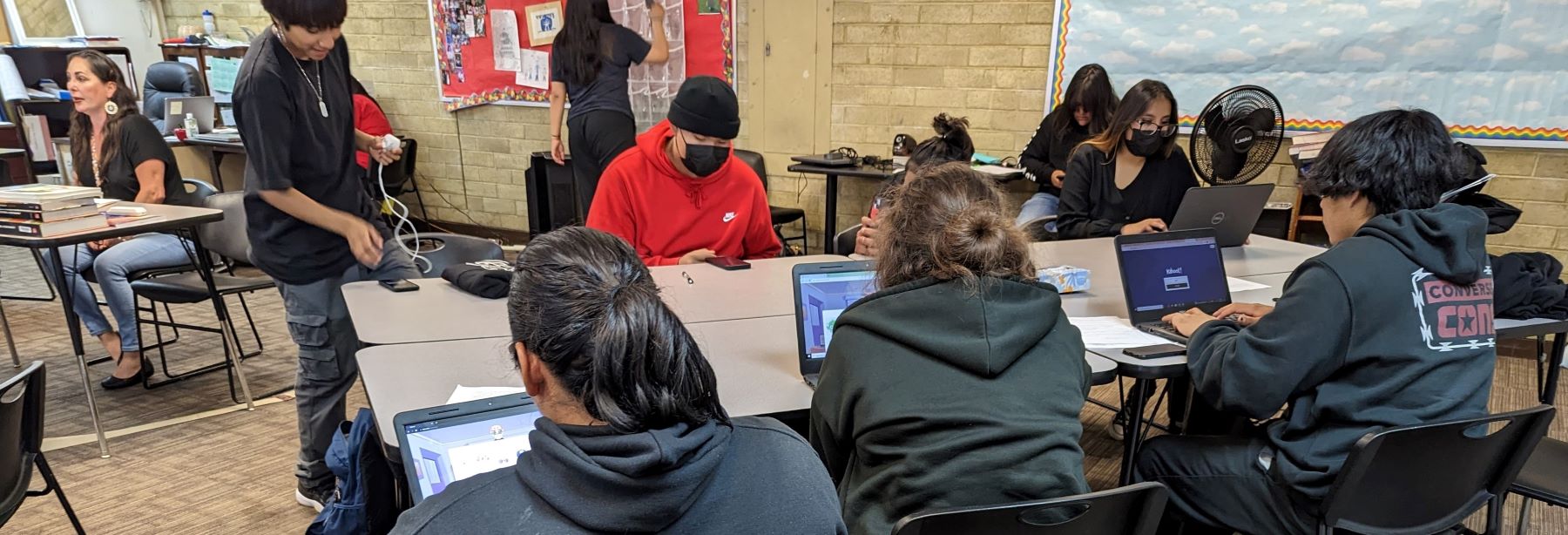 A classroom scene with students focused on their laptops, engaging in educational activities.