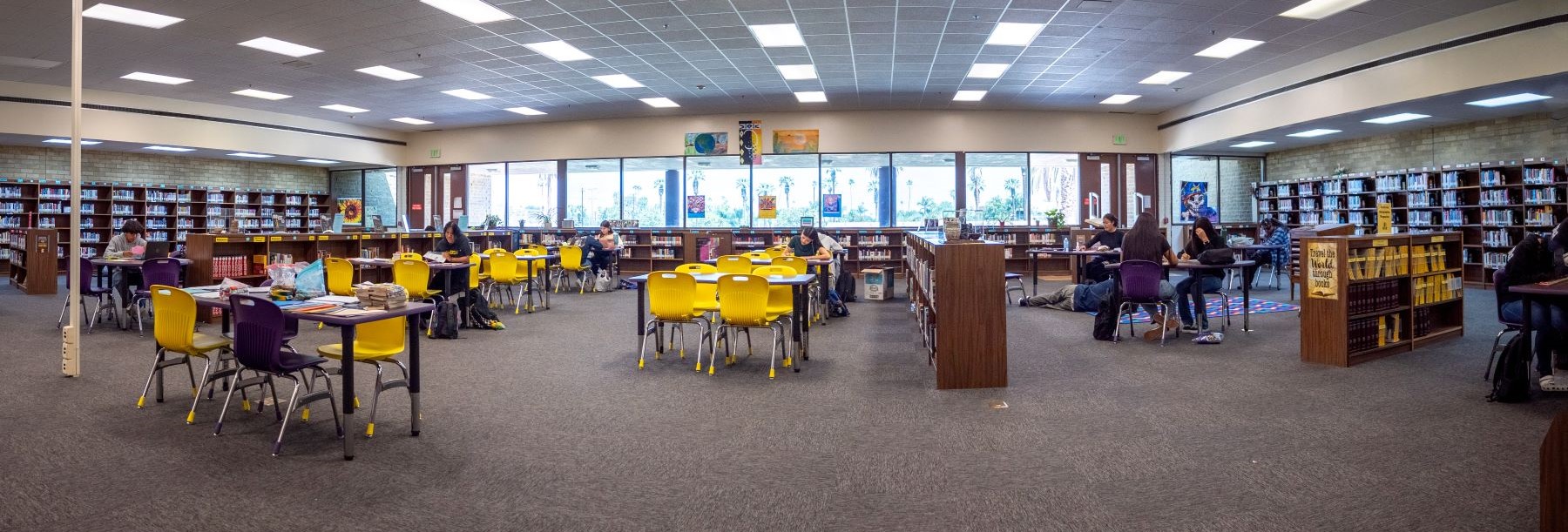 A spacious library filled with numerous tables and chairs for studying and reading.