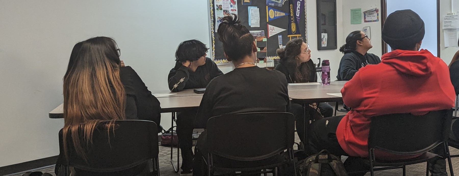 A classroom with students gathered at a table, participating in a group activity or discussion.